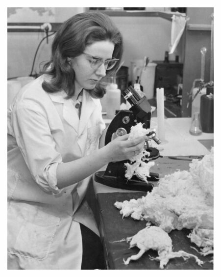 1966: Miss Mary Boyne of Aberdeen, a laboratory assistant, using a microscope to examine minute flaws in the paper, and looks at the processed rags. Image: DC Thomson archives.