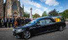 The hearse carrying the Queen's coffin passes Glenmuick Church in Ballater. Photo: Wullie Marr/DC Thomson