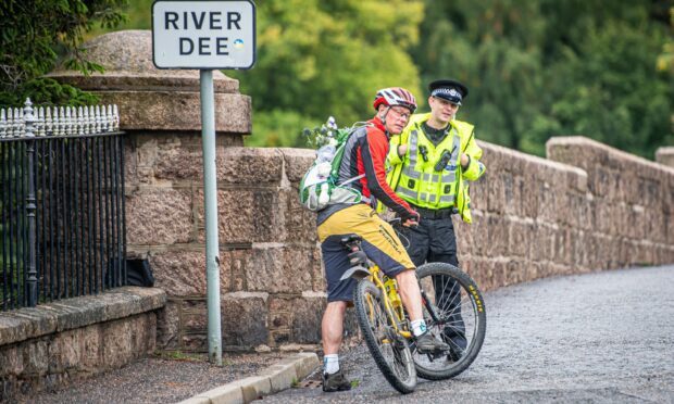 A cyclist carries flowers on his back on his way to Balmoral. Photo: Wullie Marr/DC Thomson