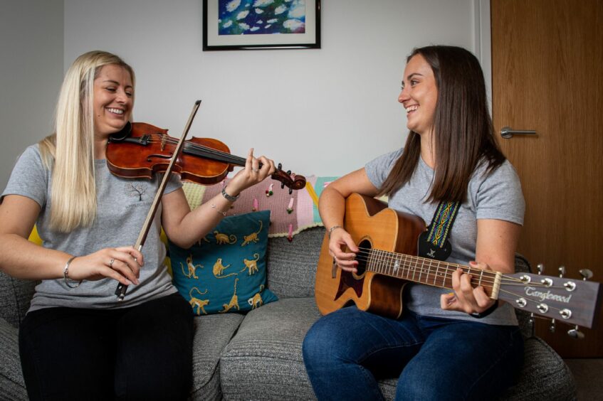 Emmeline McCracken playing violin and Nadine Allan playing guitar for a music therapy session in Aberdeen.