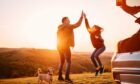 Father and daughter giving high five while camping on a hill