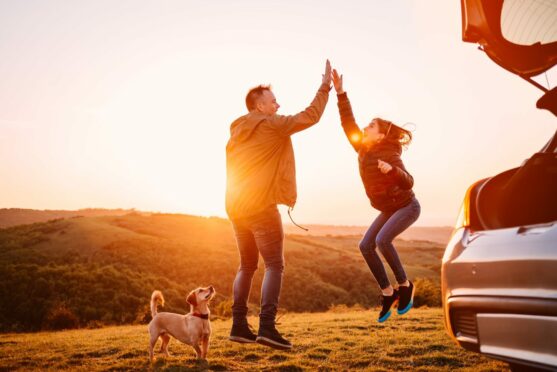 Father and daughter giving high five while camping on a hill