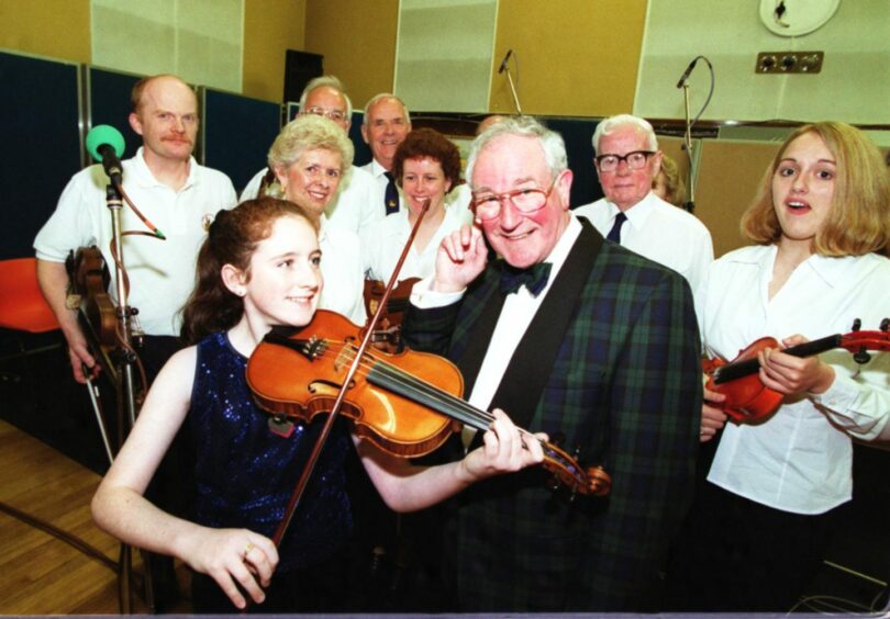 A man posing with violinists 