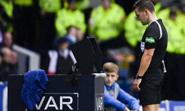 Referee Nick Walsh checks the VAR monitor for a potential penalty.