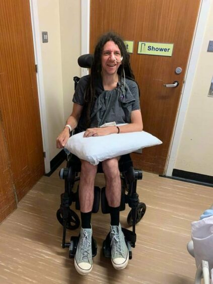 The Inverness musician was paralysed after a stoke in August 2022. He is pictured in a wheelchair.