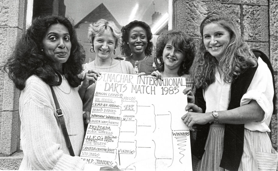 A group of women hold the scoreboard in front of the camera.