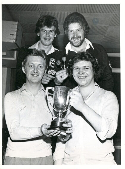 Four men, two of which are holding the Aberdeen Darts Association Pairs Cup