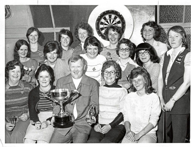 A group pose in front of a dart board at a women's aberdeen darts championship