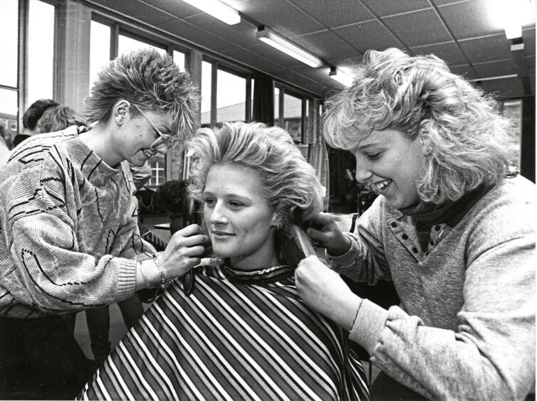 Hairdressing students cutting a woman's hair