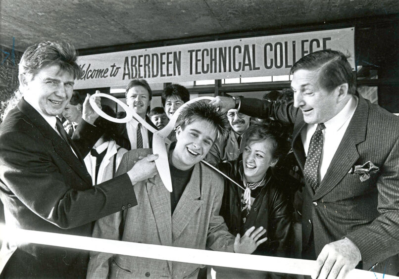 Four people ready to cut the ribbon to the Aberdeen Technical College 25th anniversary celebration