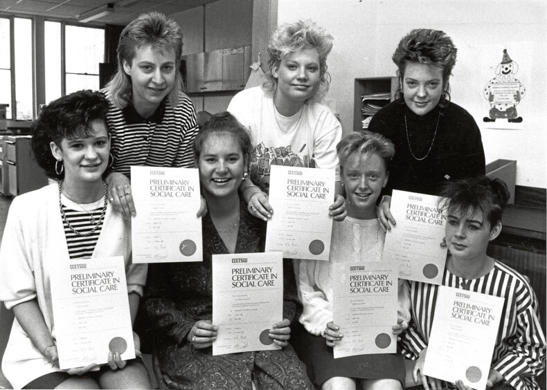 Seven girls posing together holding up certificates