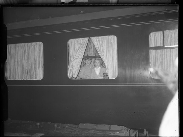 A young King Charles and Princess Royal peek out of the curtains of a train at Aberdeen station.