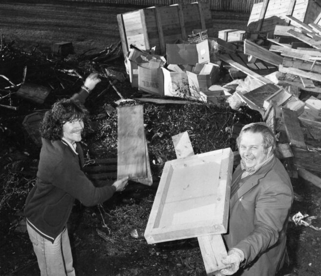 Two men contribute to a pile of wood scraps and pallets for Bonfire night Aberdeen 