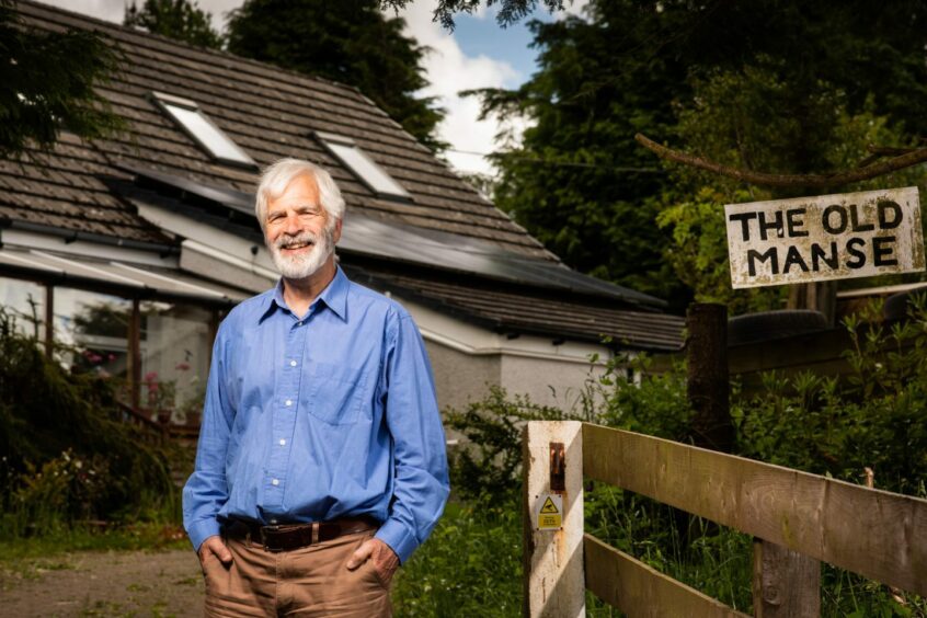 man poses in front of his home which uses one of many heat pumps in Scotland
