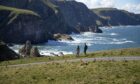 tourists look at stunning view of sea and mountains in Scotland