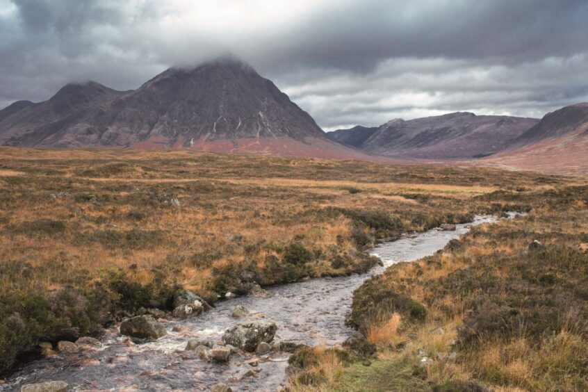 countryside scenery with mountains and a stream in Glencoe in western Scotland