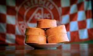 Plate of Pittodrie Pies in front of AFC flag