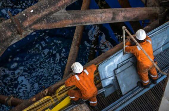 Two workers at jack up oil rig leg when checking everything in rig move operation.