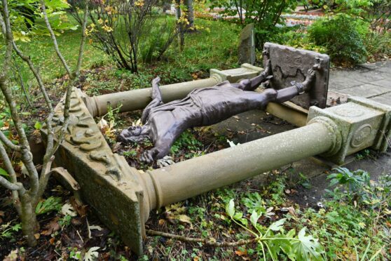 Statue toppled over among the plants at Elgin Biblical Garden