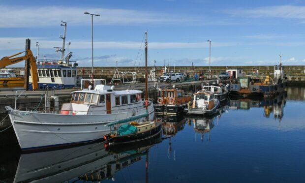 Boats at Buckie harbour on a calm day with blue sky.