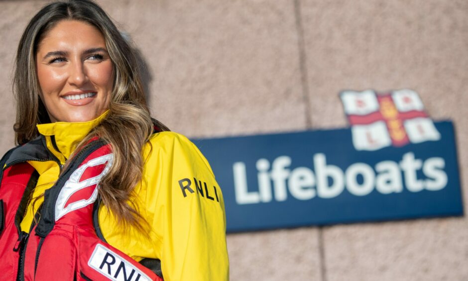 Miss European winner Sarah Patterson standing behind a sign that says 'lifeboats' at Peterhead