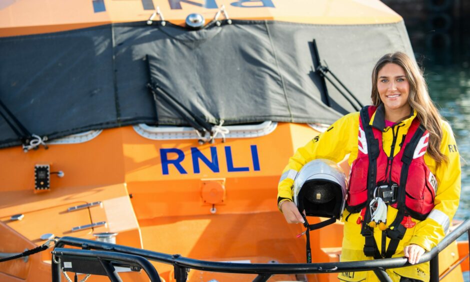 Miss European winner Sarah Patterson standing on Peterhead lifeboat holding onto her helmet