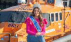 Miss European winner Sarah Patterson sitting next to lifeboat at Peterhead where she works