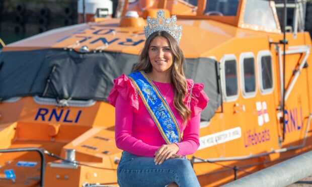 Miss European winner Sarah Patterson sitting next to lifeboat at Peterhead where she works