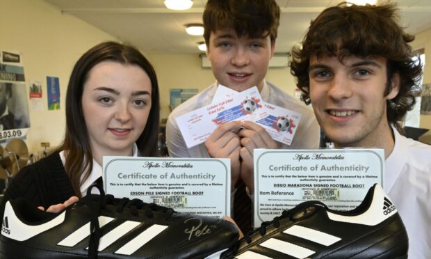 Emma Campbell, Archie Campbell and Ruairidh Poll with the signed boots which are being raffled to raise funds for the school. Image: Iain Ferguson.
