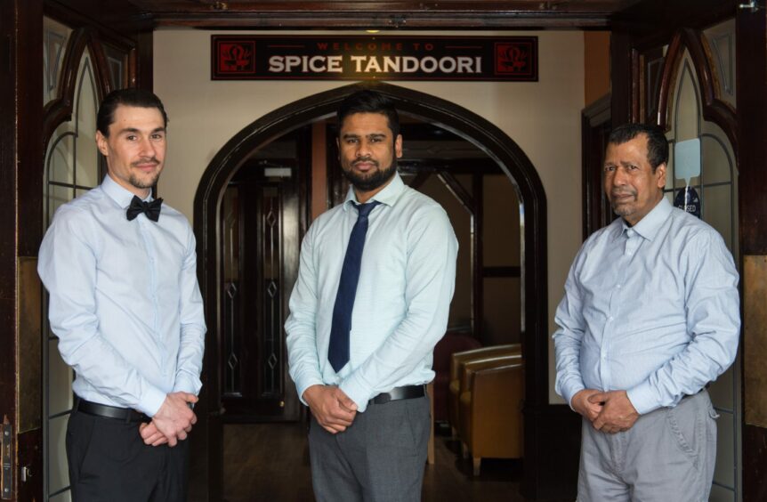 Staff standing outside Spice Tandoori with sign behind them