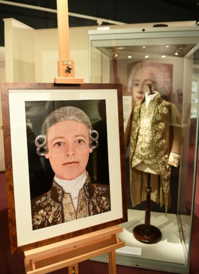 A portrait of Bonnie Prince Charles next to his jacket and waistcoat on display
