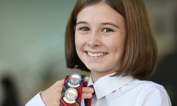 Sophie Stewart of Conon Bridge and a pupil of Dingwall Academy with her two gold badges for singing in the fluent girls competitions. Image: Sandy McCook/ DC Thomson.