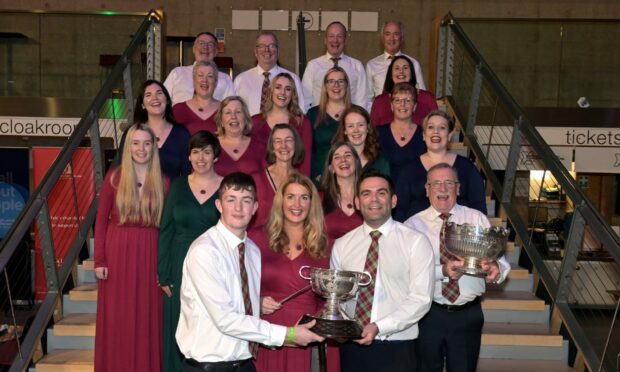 Kirsteen Menzies , conductor of the Black Isle Gaelic Choir, Dingwall with the Margrat Duncan Memorial Trophy with on the left Finlay Maclennan and on the right of the trophy Steven MacIver.