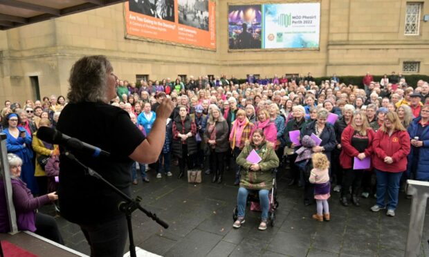 Riona White, conductor of Burach, conducts the massed choirs outside the Perth Concert Hall. Image: Sandy McCook/ DC Thomson.
