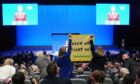 Anti-fracking demonstrators hold up a banner as Prime Minister Liz Truss delivers her keynote speech at the Conservative Party annual conference in Birmingham.
