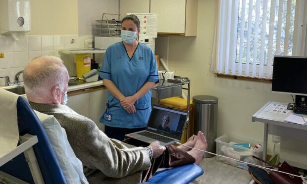 Podiatry professional lead Claire Mackenzie and (on screen) advanced practice podiatrist Fiona Main with with a patient in Torridon GP surgery in Inverness.