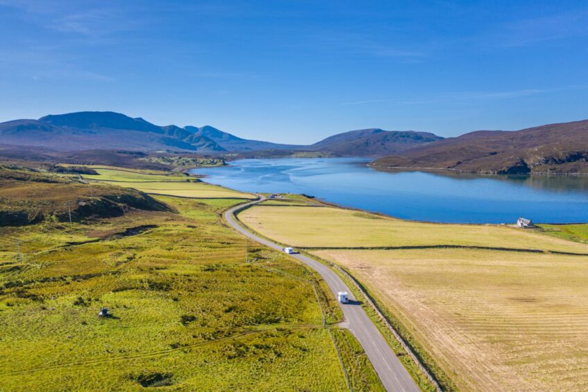 Drone shoot capturing motorhomes on scenic A838 road near Kyle of Durness and Beinn Spionnaidh at bright day in North West Highlands of Scotland - NC500 Route