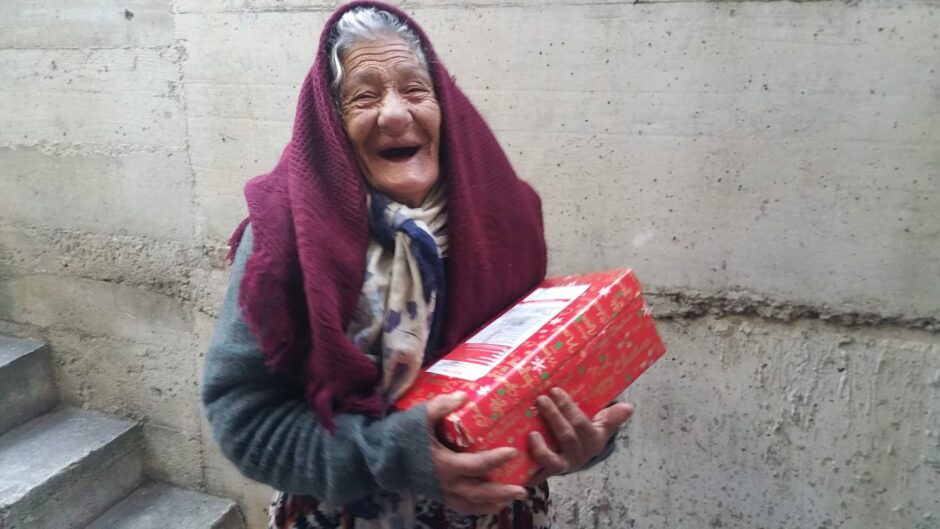 old woman smiling when receiving a Christmas shoebox