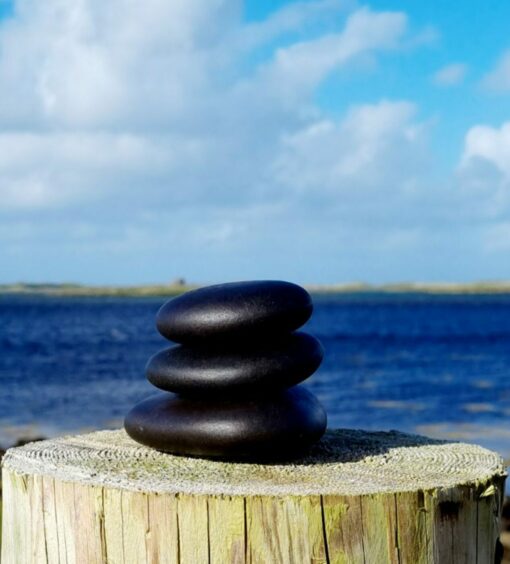 Massage stones stacked in front of a view of the sea.