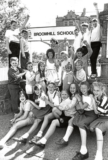 Broomhill School pupils celebrating outside the school, one girl is on her mum's shoulders