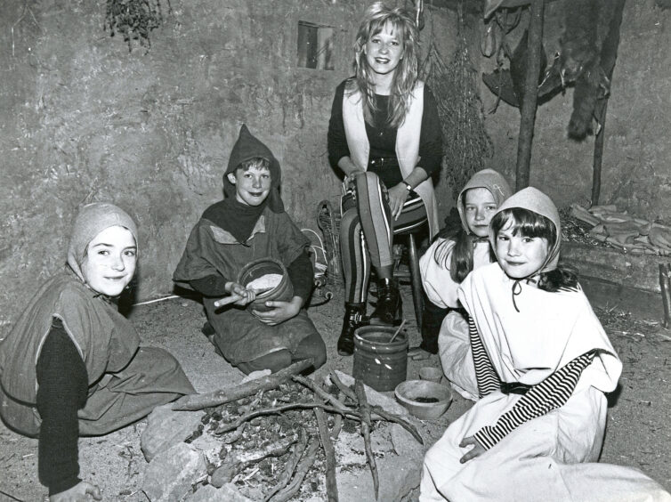 Five students dressed in medieval-style clothing sat around a campfire.