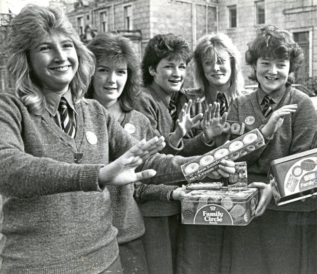 Five students holding tins of biscuits