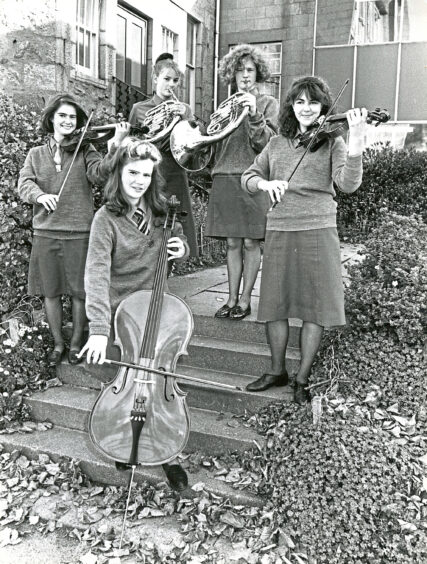 Five girls holding their instruments smiling at the camera
