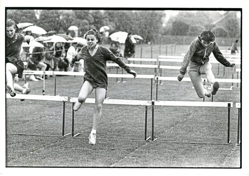 A girl taking part in a hurdle race, she is in the lead.