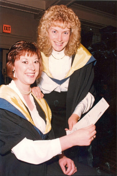 Two women smiling at the camera, holding a certificate between them