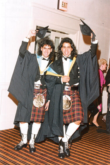 Two borthers holding their caps in the air after graduating