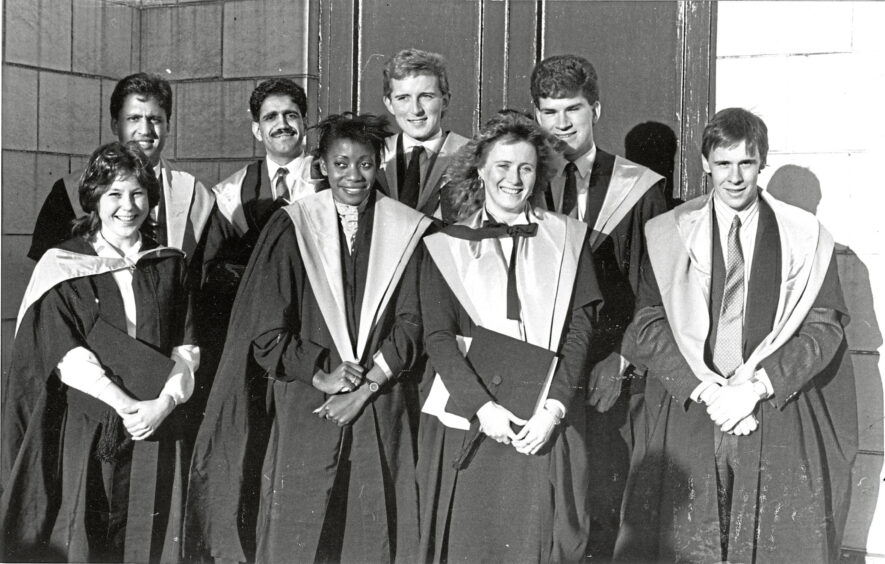 Eight graduates smiling at the camera 