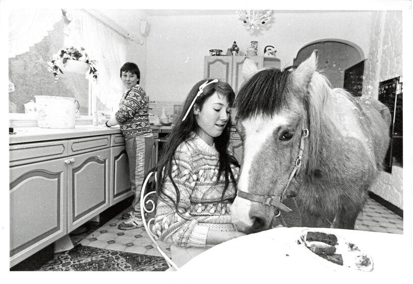 1986 - Tino sneaks into the kitchen for a quick snack from Rhodella as brother William tackles the washing up.