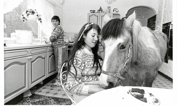 1986 - Tino sneaks into the kitchen for a quick snack from Rhodella as brother William tackles the washing up.