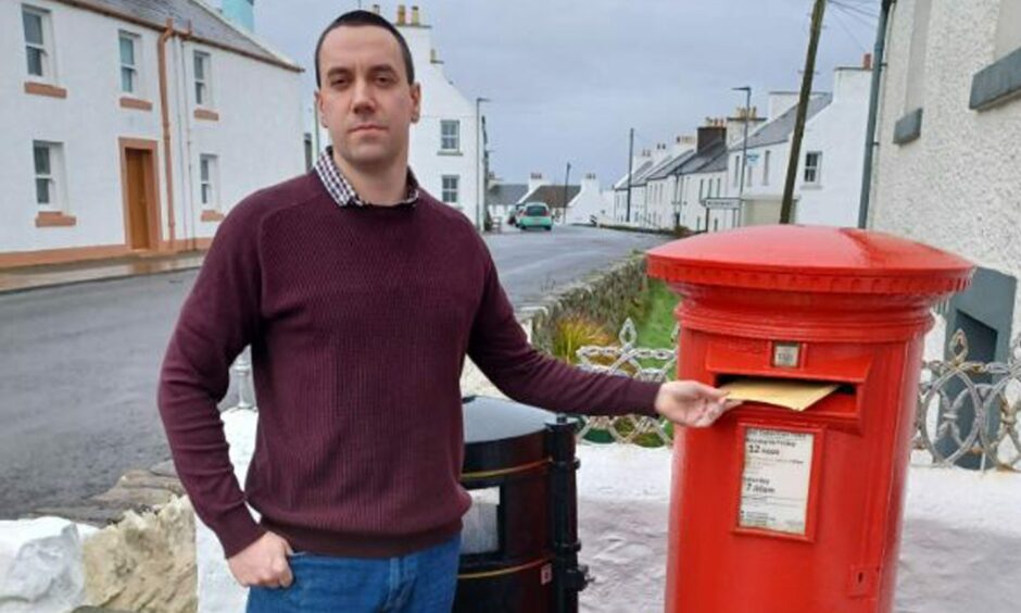 Councillor Alastair Redman at a red postbox on Islay. 